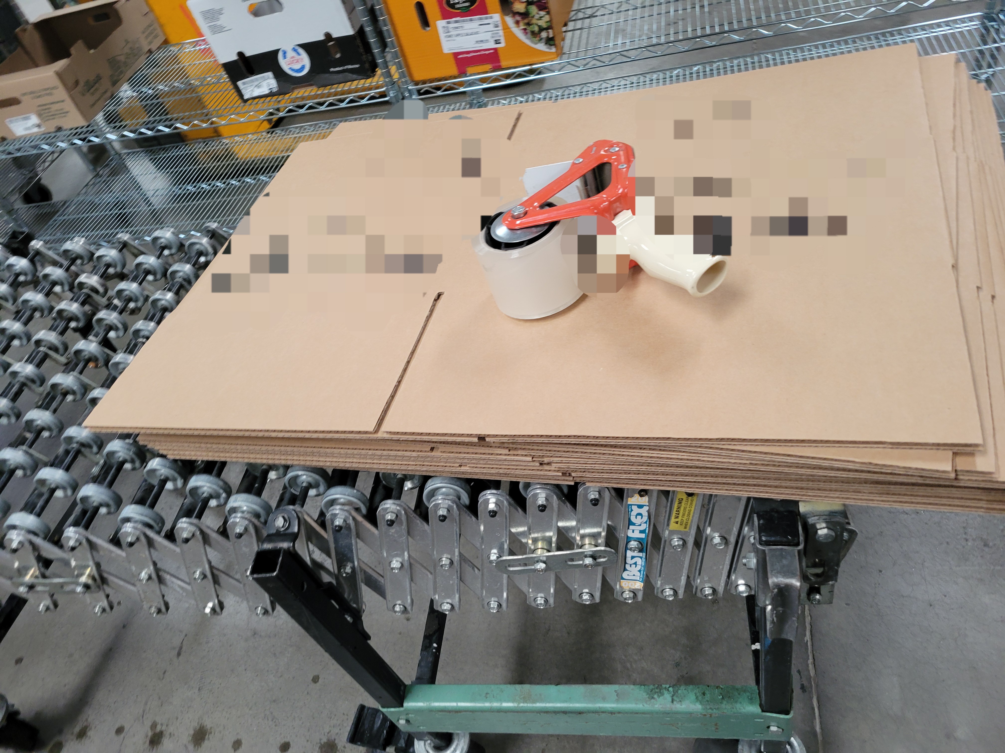Cardboard boxes with a tape gun on top on a conveyor belt.